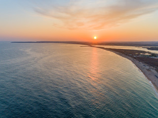 Aerial sunset view of Praia dos Tres Irmaos (Three Brothers beach) in Alvor, tourist destination in Algarve Coast, Portugal.