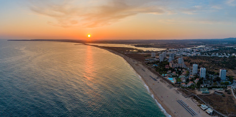 Aerial sunset view of Praia dos Tres Irmaos (Three Brothers beach) in Alvor, famous tourist destination in Western Algarve Coast, Portugal.