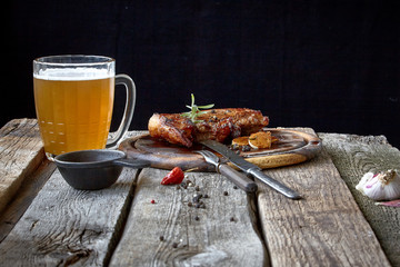 Still life with a big fried steak, a glass of beer, mustard and cutlery on an old wooden tabletop, the concept of Oktoberfest and St. Patrick's Day