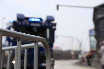 absperrgitter und im hintergrund unscharf ein Polizei Wasserwerfer