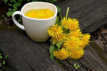 Dandelion flower tea infusion in white cup close up