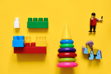 Flat lay of plastic and eco wooden toys. Developing games. Yellow background