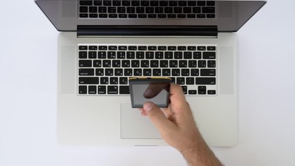 Text hands of a young man taking a screenshot of a laptop using a mobile phone on a white office desk top view