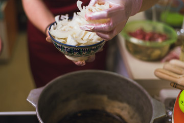 Woman puts onions in a pan with butter. The cook fries onion rings in a pan in a large amount of vegetable oil.