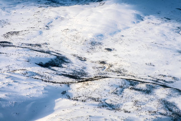 Fototapeta na wymiar Aerial view of snowy landscape in winter with mountains and forest in Norway