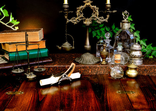 Spell books and bottles, dark candlestick with balance scale on a wooden table. Recipes of magic potions. Concept of alchemy. Imagination of the reader, inspiration for writing. 