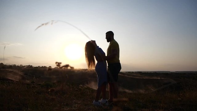 Silhouette of a charming young couple in rural landscape at sunset. A couple in love in the sunset light