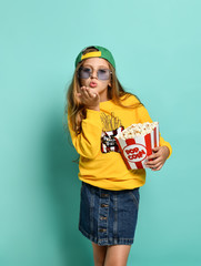 Young cute woman eating popcorn over green background.