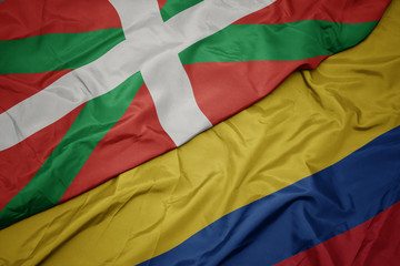 waving colorful flag of colombia and national flag of basque country.