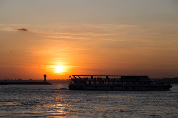 people sitting at the seaside and watching sunset and ferry.