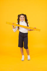 Fototapeta na wymiar School student study geometry. Tell me about distance. Kid school uniform hold ruler. Pupil cute girl with big ruler. Geometry school subject. Education and school concept. Sizing and measuring