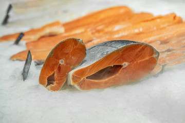 Pieces and fillet of salmon to portions on ice in supermarket close-up. Sale of seafood, fish. Open showcases , counter of seafood market