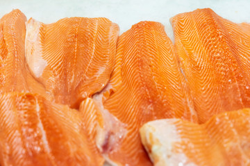 Fillet of salmon to portions on ice in supermarket. Sale of seafood, fish. Open showcases , counter of seafood market