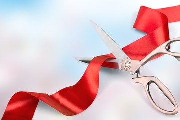 Red ribbon with iron scissors on blurred background