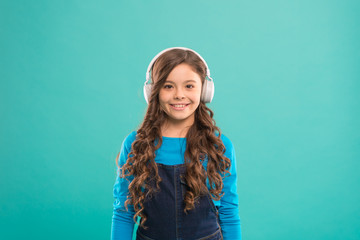 Fototapeta premium Let the music take you away. Cute little child listening to music playing in stereo headphones. Adorable girl enjoying music on blue background. Music education for small children