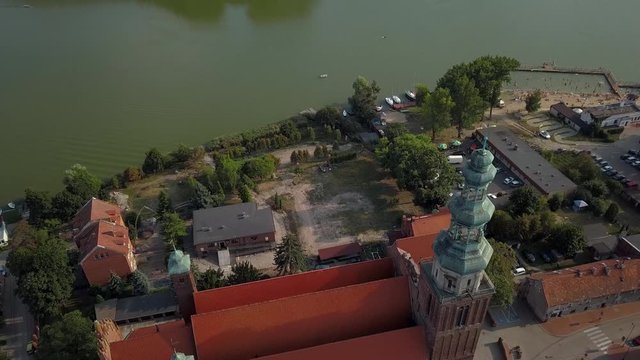 Aerial: Flight around the old medieval church in Chelmza, old city in Poland. View of the lake beach located near the city town.