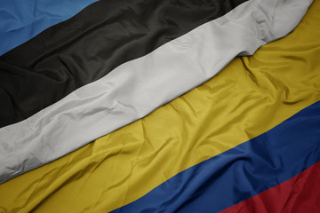 waving colorful flag of colombia and national flag of estonia.