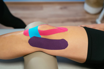 The knee of a patient with three medical straps, purple, light blue and pink. Concept of muscle...
