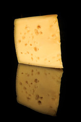 vertical view of hard porous yellow cheese piece with holes