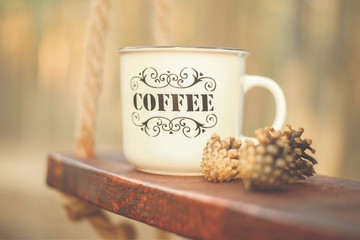 a large Cup labeled coffee stands on a wooden swing