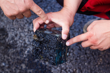 Road workers take a cube of asphalt