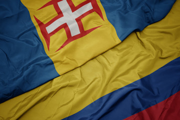 waving colorful flag of colombia and national flag of madeira.