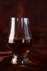 Glass of bourbon on dark silk background