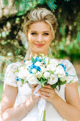 Cute bride with bouquet in hands on nature background