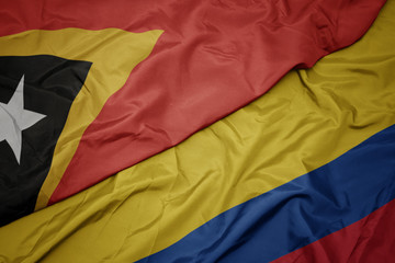 waving colorful flag of colombia and national flag of east timor.