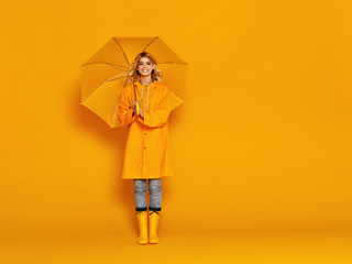 young happy emotional girl laughing  with umbrella   on colored yellow background.