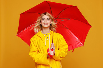 young happy emotional cheerful girl laughing  with red umbrella   on colored yellow background.