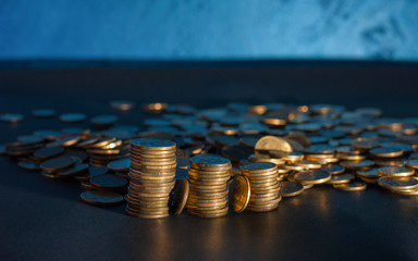 Banking and money trading. Golden metal coins stacked in different combinations on dark blue blurred background. Serbian metal coin, copy space