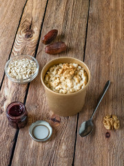 Oatmeal porridge with dates in a cardboard cup. Healthy food and diet concept.