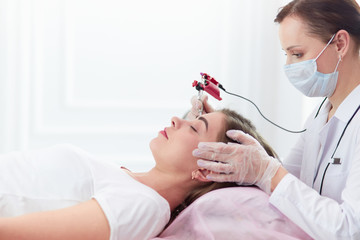A young girl having red lips permanent makeup, micropigmentation