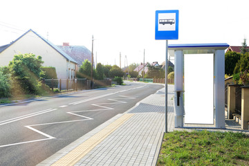 Bilbord reklamowy na przystanku autobusowym w centrum wioski, promienie słoneczne.