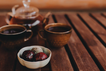 Handmade sweets from a small pastry shop with two cups and a teapot on a cozy wooden background. Copy space.