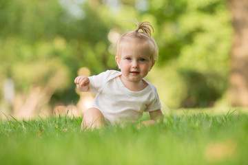 baby girl in a white sandpit on the green grass playing pyramid