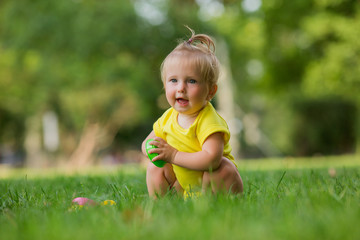 baby girl in a white sandpit on the green grass playing pyramid