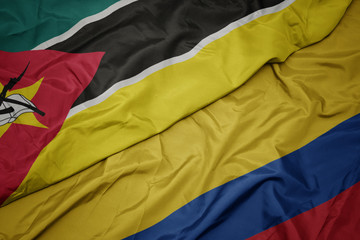 waving colorful flag of colombia and national flag of mozambique.