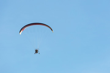 bright paraglider with a motor flies in the blue sky