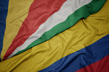 waving colorful flag of colombia and national flag of seychelles.