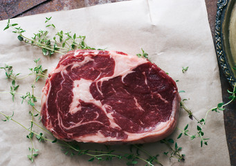 Fresh raw beef ribeye steak with rosemary top view