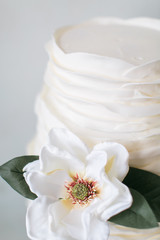 Minimal white wedding cake with one white flower, light blue background, copy space