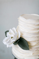 Fototapeta na wymiar Minimal white wedding cake with one white flower, light blue background, copy space