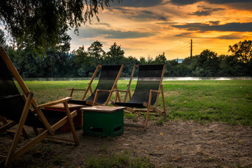 Chairs and primitive table by the river at sunset