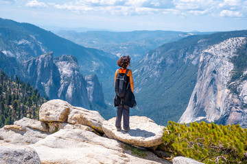 A young woman in pink and black at Sentinel Dome looking at El Capitan, Yosemite National Park....