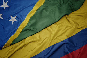 waving colorful flag of colombia and national flag of Solomon Islands .