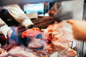 Close up on butcher's hands in gloves working in butchery.