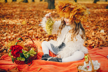 Cute child in a autumn park. Elegant little lady with fruits