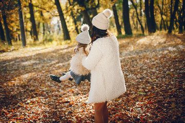 Fototapeta premium Beautiful mother with daughter. Family in a autumn park. Golden autumn